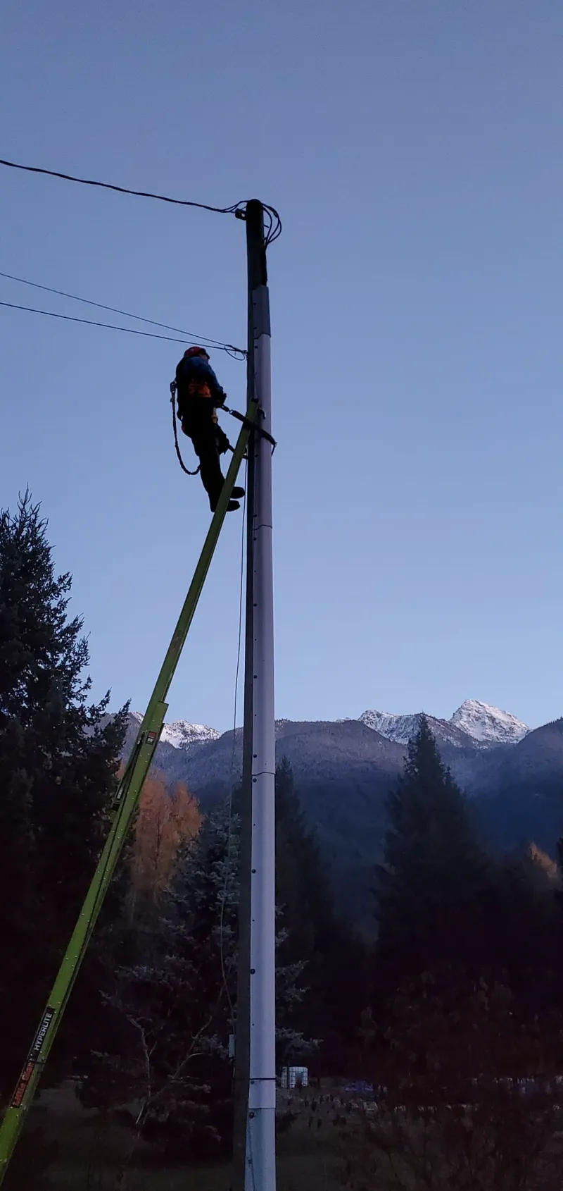 EK crew member working on a utility pole in a remote mountain community